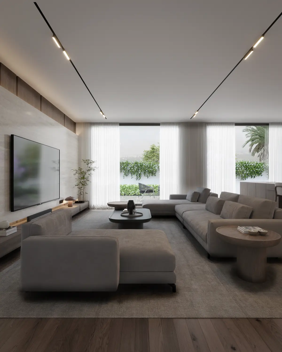 The Grid House living room render. L-shaped sectional sofa facing a travertine TV wall, full-height windows to lush garden with palm tree, residential interior, Lahore.