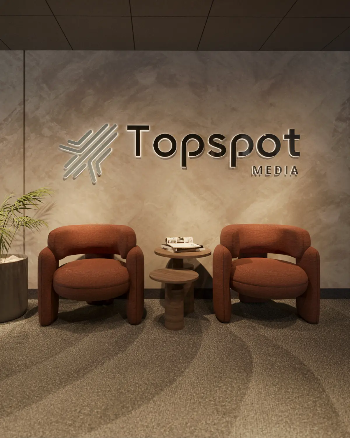 TopSpot Media reception render. Illuminated brand logo wall above two terracotta boucle armchairs and a sculptural walnut side table, corporate fitout, Lahore.